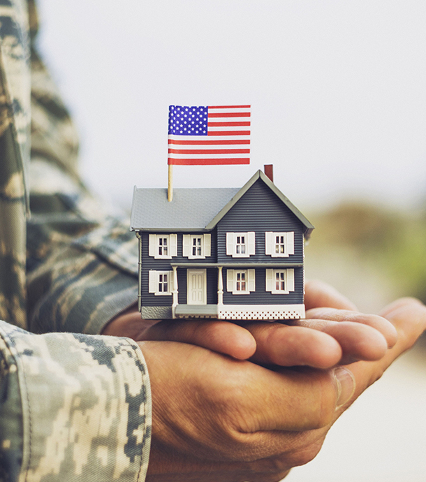 Uniformed military service member embracing family on front porch of their home